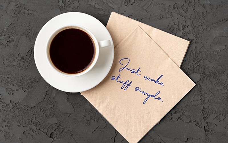 Top view of coffee cup with napkin that says Just make stuff simple