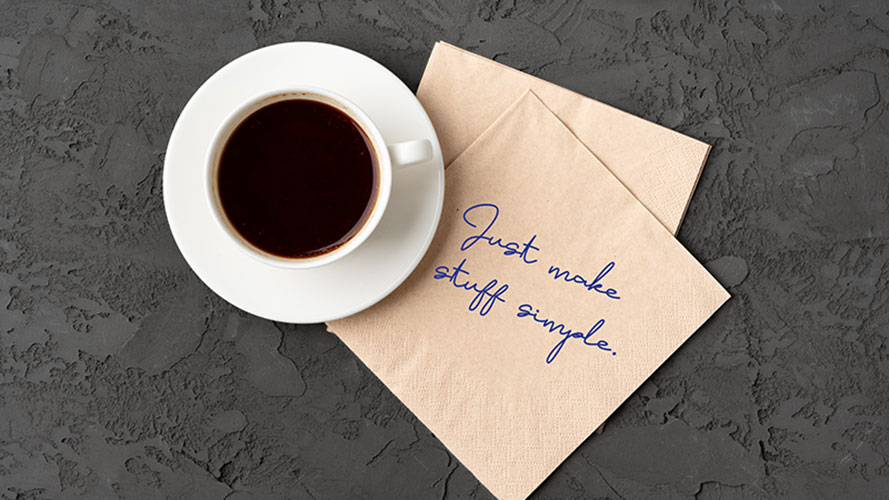 Top view of coffee cup with napkin that says Just make stuff simple